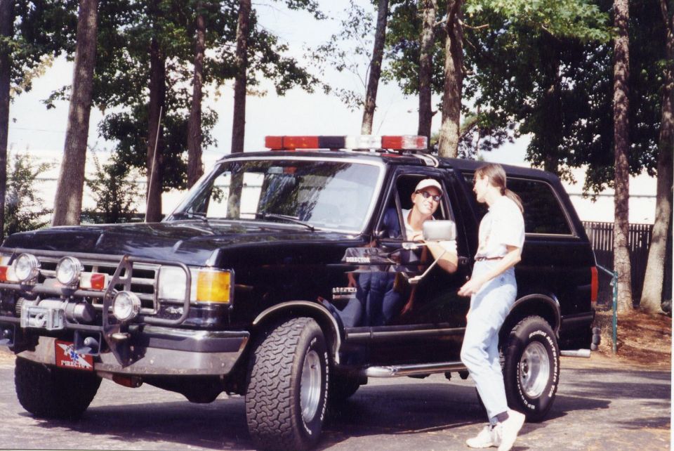 Black Ford Bronco SUV with light bar and winch, two people standing next to it.