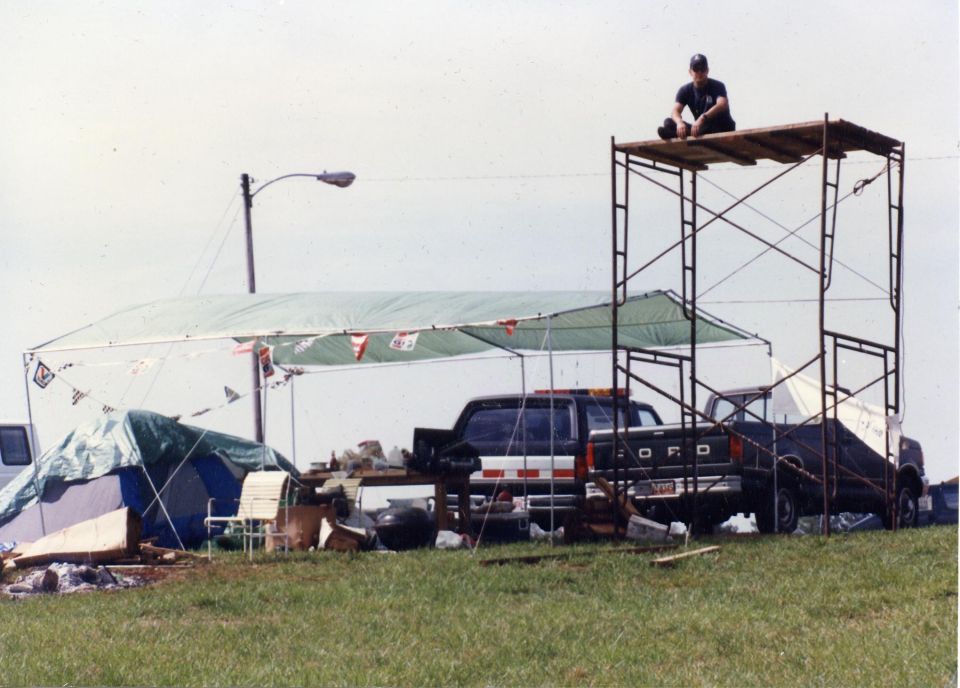 Person on scaffolding overlooking a campsite with a Ford pickup truck.