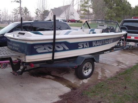 1988 Ford Bronco - A white and blue Ski Nautique boat is parked on a trailer, with the number "2001" visible on its side. The boat is positioned in front of a…