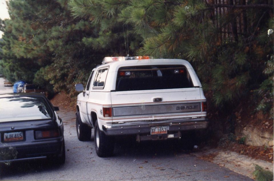Rear view of a white Chevrolet SUV with light bar and license plate XF 1653.
