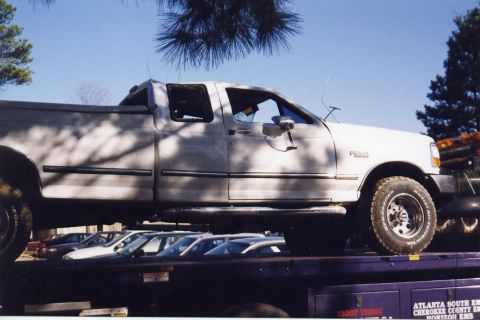 1988 Ford Bronco - A white pickup truck is loaded onto a dark-colored car carrier. The truck has a crew cab and a visible tire with "BFGoodrich Radial All-Ter…