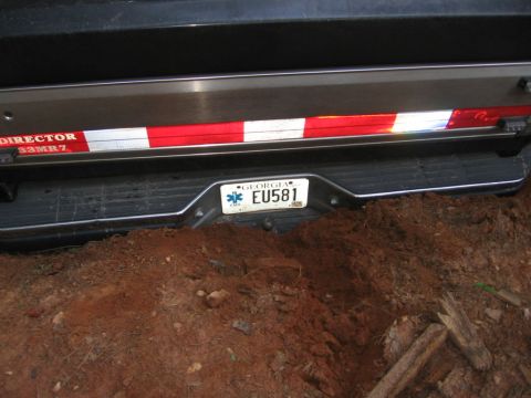 1988 Ford Bronco - The rear bumper and license plate of a vehicle are partially buried in dirt. The license plate reads "Georgia EU581".