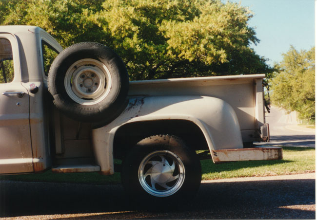 Left rear bedside of white classic stepside pickup with spare tire behind cab