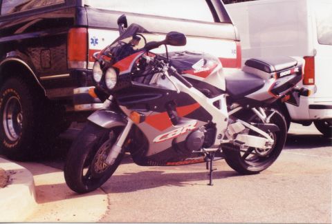 1988 Ford Bronco - A silver, red, and black Honda CBR 900R motorcycle is parked next to a black Ford Bronco with red emergency lights. The motorcycle is in th…