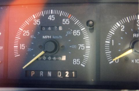 1988 Ford Bronco - The image shows a close-up of a vehicle's dashboard, focusing on the speedometer and gear selector. The speedometer reads approximately 55…
