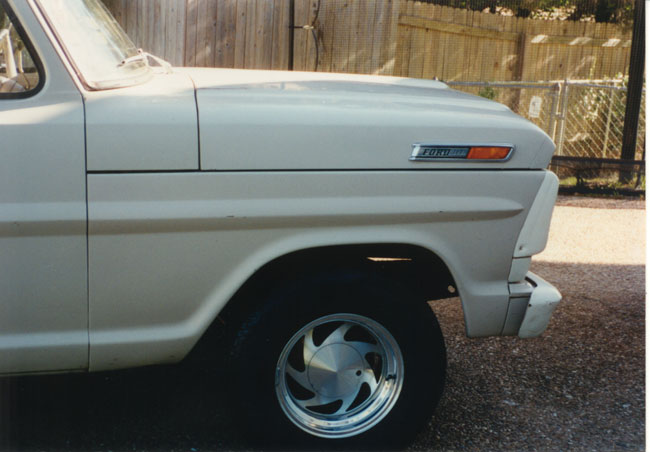 Right front fender of white classic Ford pickup with FORD badge and polished five-spoke wheel