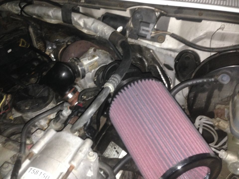 Engine bay of a Ford F-250 with turbocharger and pink air filter.