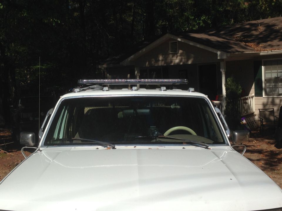 White Ford F-250 pickup truck with a roof-mounted light bar.