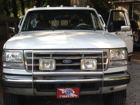 1997 Ford F-250 - The front view of a white Ford F-250 pickup truck with a chrome grille guard and auxiliary lights. A red and white "PARAMEDIC" license plat…
