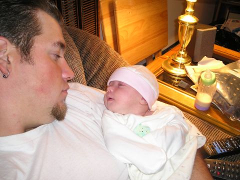 1994 Ford F-150 - A man holds a baby while sitting on a couch, with a lamp and baby bottle visible on a nearby table.
