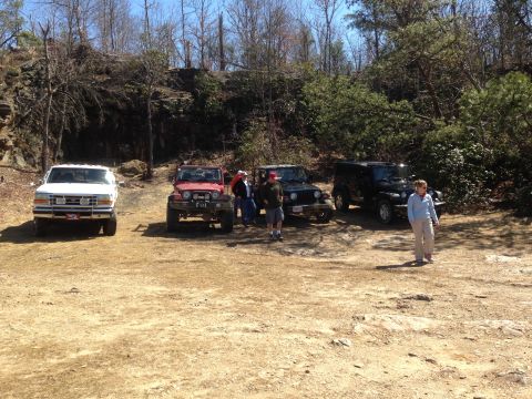 1997 Ford F-250 - A group of Jeeps and a white Ford pickup truck are parked on a dirt lot with a rocky hillside and trees in the background. A woman in a lig…
