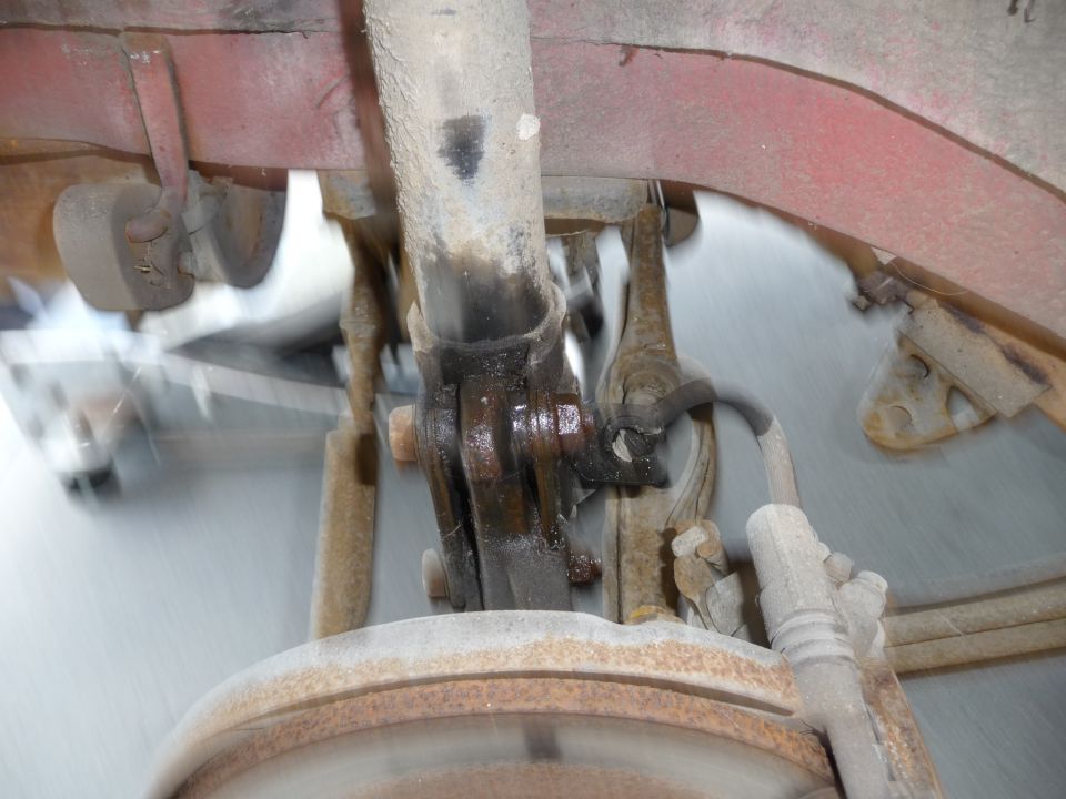 Rear suspension of a vehicle with shock absorber, brake rotor, and leaf spring, motion blurred.