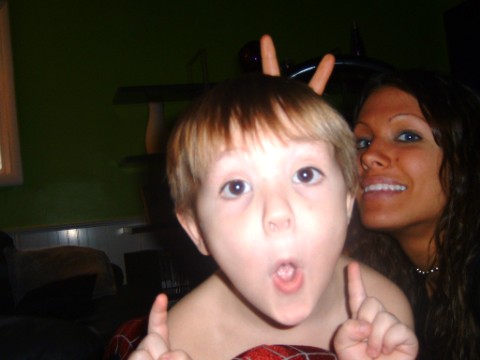 1997 Ford Taurus - Child makes bunny ears gesture while a woman smiles in the background. Supermotors logo is visible.
