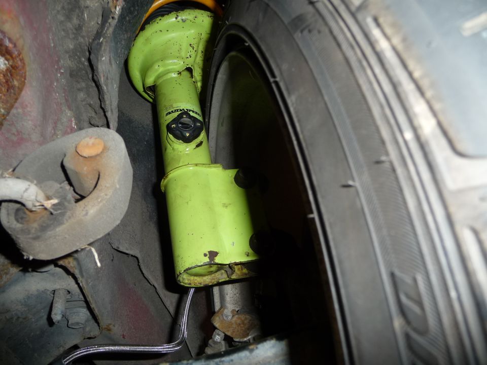 Close-up of a green Mazda Speed shock absorber on a vehicle suspension.