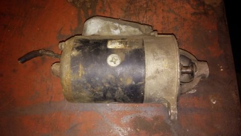 1995 Ford Bronco - Starter motor part shown on a red surface. The registry claims it is from a 1995 Ford Bronco, but this is unconfirmed.