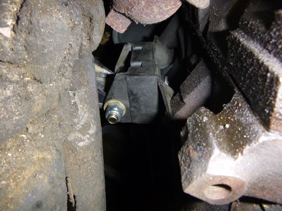 Close-up of a car engine mount with bolt and washer between engine parts.
