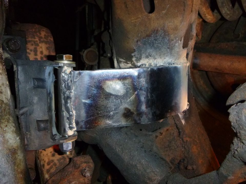 Custom welded metal bracket attached to a vehicle frame and rubber mount.