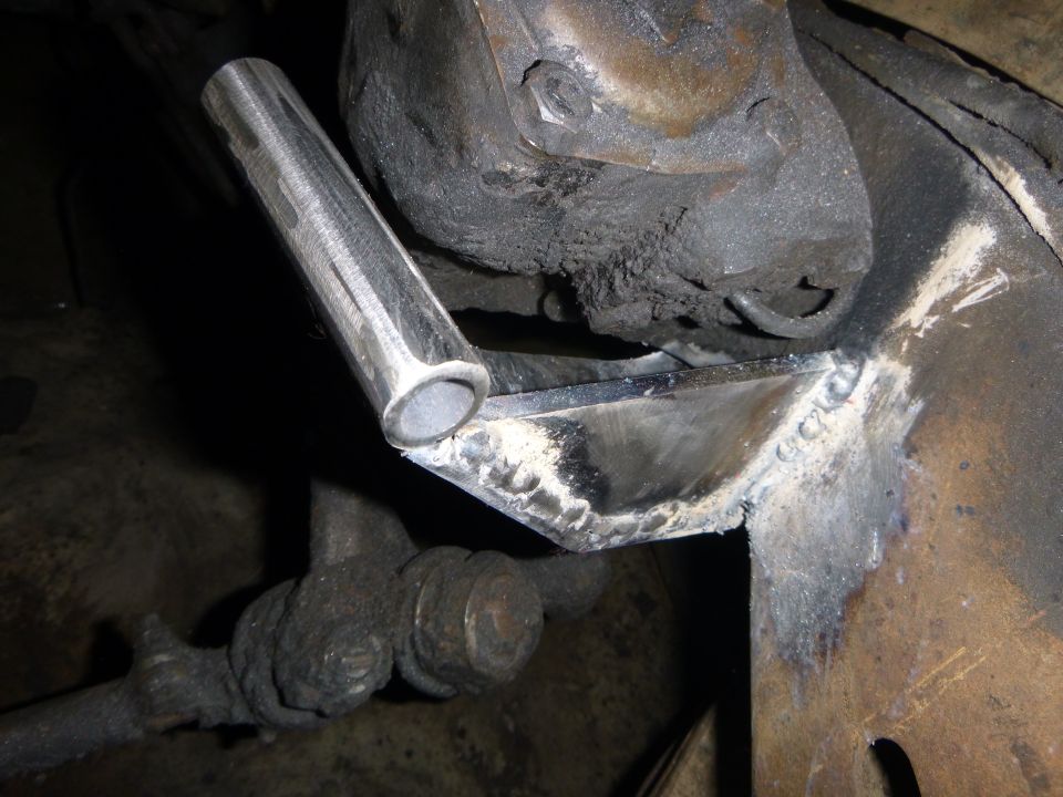 Welded metal bracket on rusty vehicle frame with metal tube.