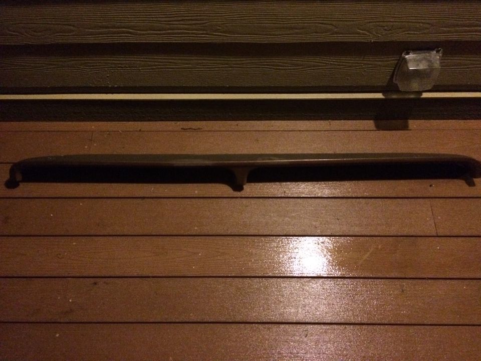 Dark curved vehicle trim piece on a wooden deck
