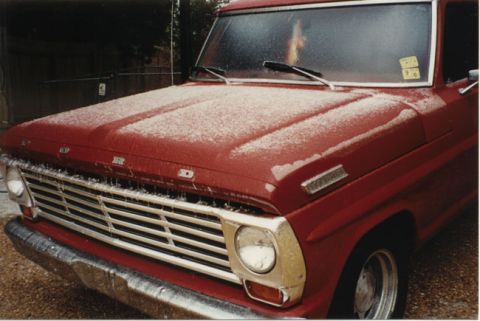 1967 Ford F-100 - A red 1967 Ford F-100 pickup truck is covered in a light dusting of snow.