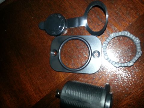 1994 Ford Bronco - Photograph of disassembled USB charger socket mounting bezel, nut and body parts, not a document.