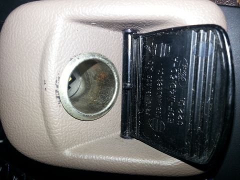 1994 Ford Bronco - Close-up photo of a beige interior 12V power-point housing with Ford molded part numbers on the hinged cover.