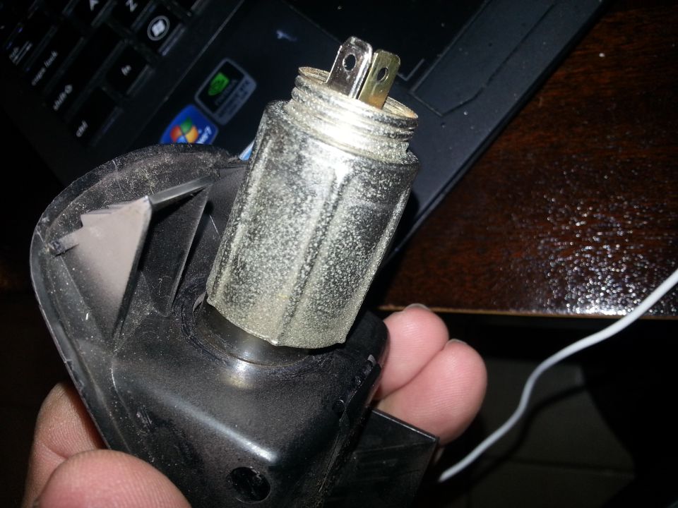 Hand holding a corroded cigarette-lighter heating element removed from its socket