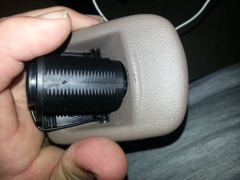 1994 Ford Bronco - Close-up photo of a beige interior power-point bezel with its black cylindrical socket inserted.