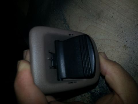 1994 Ford Bronco - Photo of a hand holding a beige interior power-point bezel with a hinged black cover.