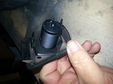 1994 Ford Bronco - Photo of a black 12V power-socket barrel and mounting bracket held by a hand.