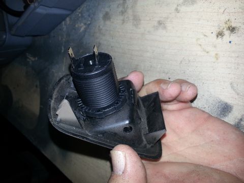 1994 Ford Bronco - Photo of a black 12V power-socket barrel mounted in its bracket, held by a hand.
