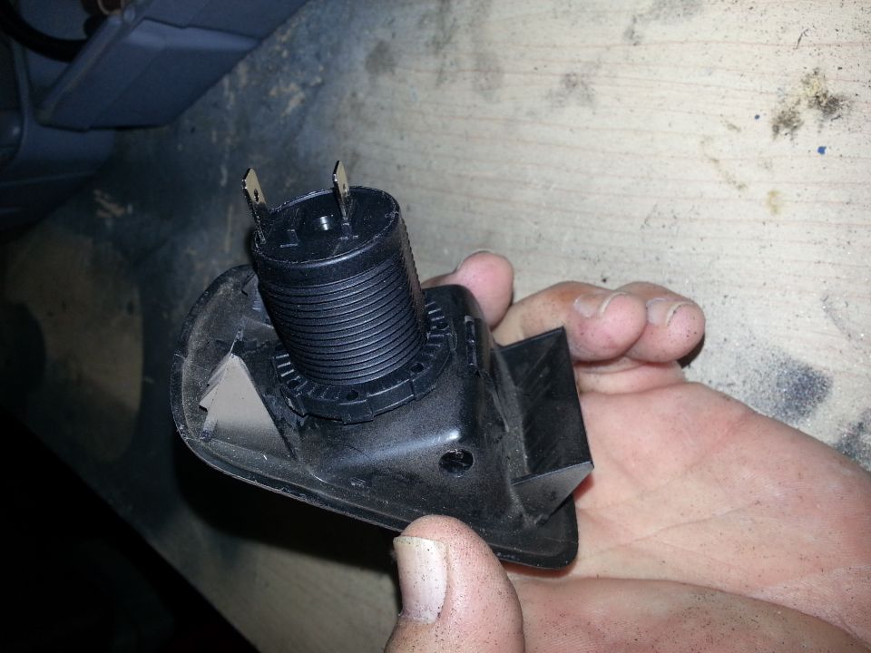Black power-socket barrel mounted in a bracket held next to a hand