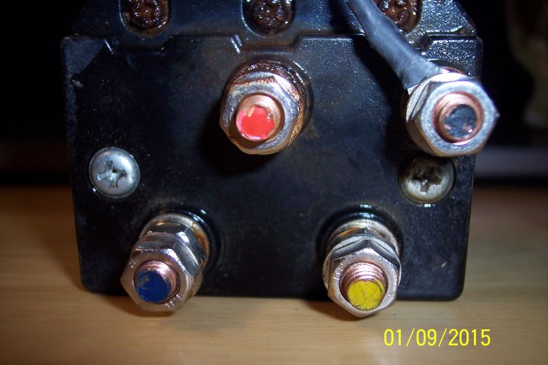 Close-up of winch solenoid terminals with red, blue, and yellow caps.