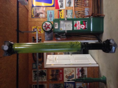1979 Ford Bronco - A green driveshaft is mounted horizontally in front of a vintage Sky Chief gasoline pump and a wall decorated with vintage advertisements.…