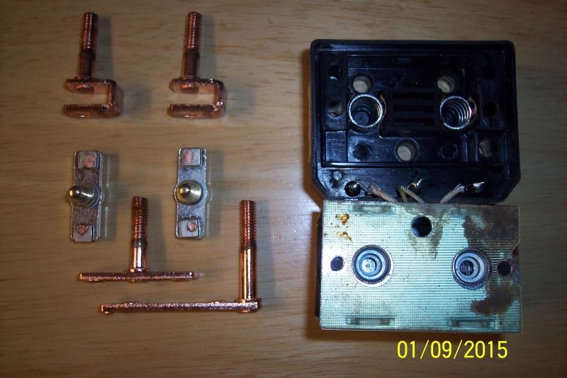 Copper electrical parts and a disassembled circuit breaker on a wooden surface.