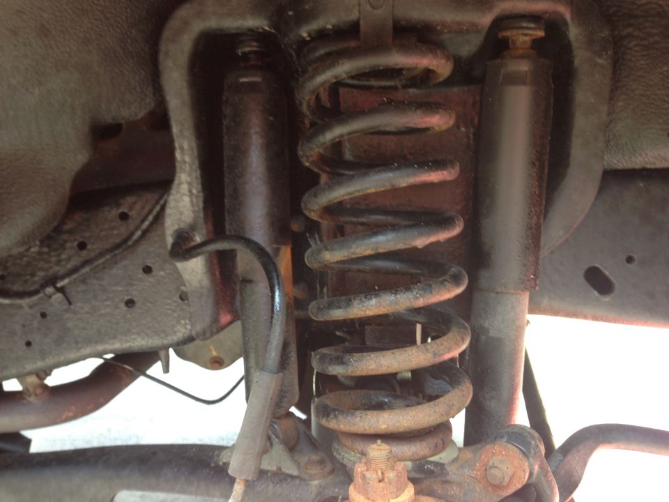 Rear suspension components including coil springs and shock absorbers, with visible rust