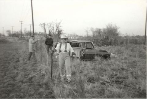 1967 Ford F-100 - A pickup truck sits abandoned in a field, with people standing nearby.