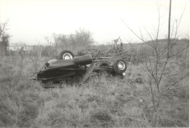 Vintage black and white photo of an overturned truck chassis lying in a field