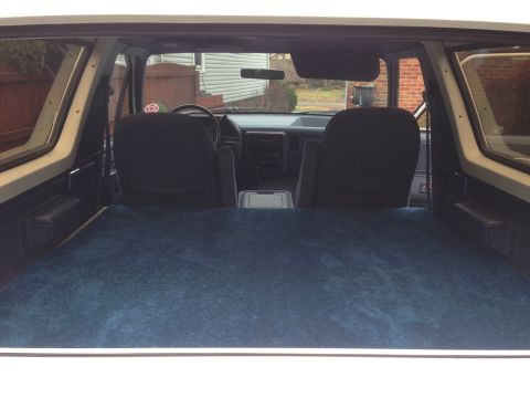 1989 Ford Bronco - The interior of a Ford Bronco shows a carpeted rear area and the front cabin with seats and dashboard.