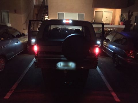 1996 Ford Bronco - Rear view of a 1996 Ford Bronco parked at night, showing its taillights and spare tire.