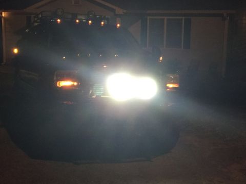 2005 Ford Excursion - Front view of a dark Ford Excursion with its headlights illuminated, parked in front of a residential building at night.