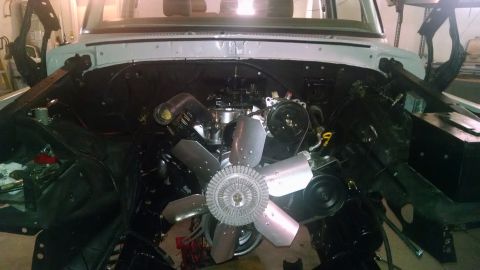1979 Ford Bronco - The engine compartment of a vehicle is shown with the engine and cooling fan prominently displayed.