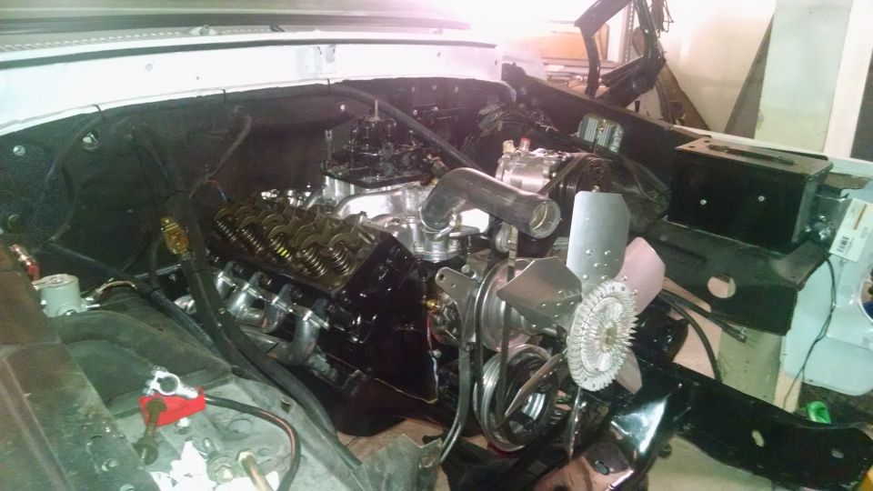 Engine with chrome headers and black valve covers, visible fan and carburetor