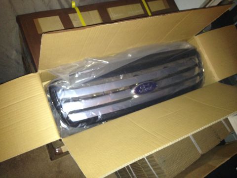 2004 Ford Crown Victoria - A new Ford grille, identified as a 2004 model, is packaged in a cardboard box.