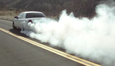 2004 Ford Crown Victoria - A white 2004 Ford Crown Victoria performs a burnout, kicking up a large cloud of smoke.