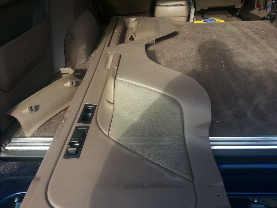Tan interior door panel and trim pieces laid out in the cargo area of a vehicle