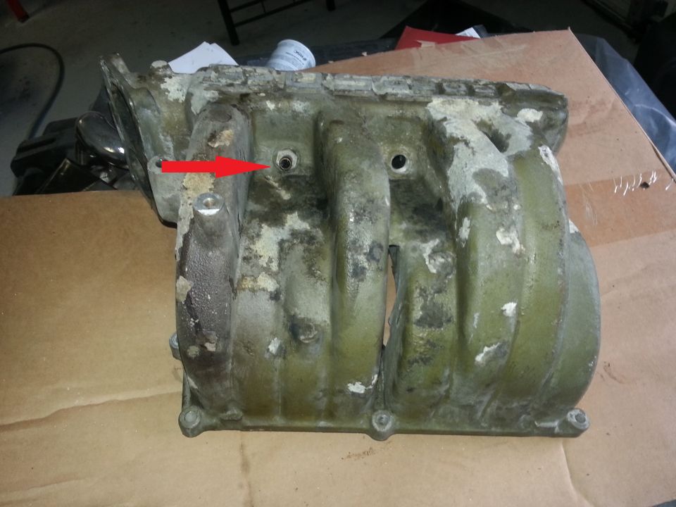 Green intake manifold with red arrow pointing to a bolt hole