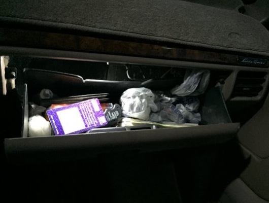 Open glove box filled with various items including a purple box and plastic bags