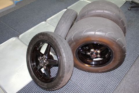 2003 Ford Crown Victoria - A set of drag racing tires and wheels are laid out on a checkered floor.