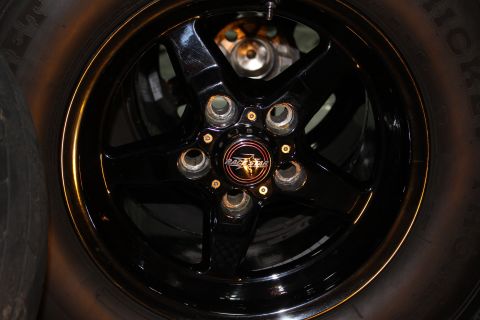 2003 Ford Crown Victoria - A close-up view of a black five-spoke wheel a Race Star center cap and part of a tire.